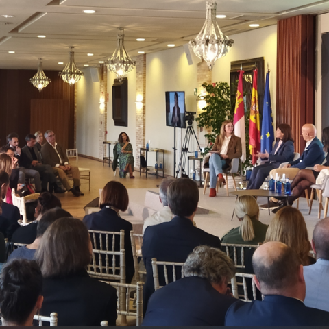 Mesa redonda con pantalla de fondo y asistentes mirando