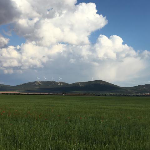 cielo azul con nubes con colinas al fondo con aerogeneradores