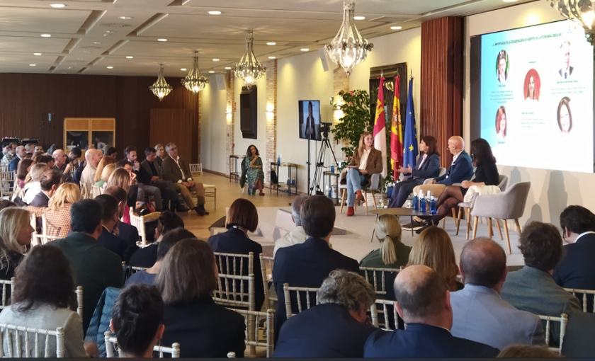 Mesa redonda con pantalla de fondo y asistentes mirando