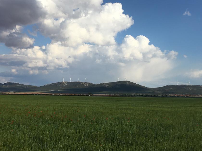 cielo azul con nubes con colinas al fondo con aerogeneradores